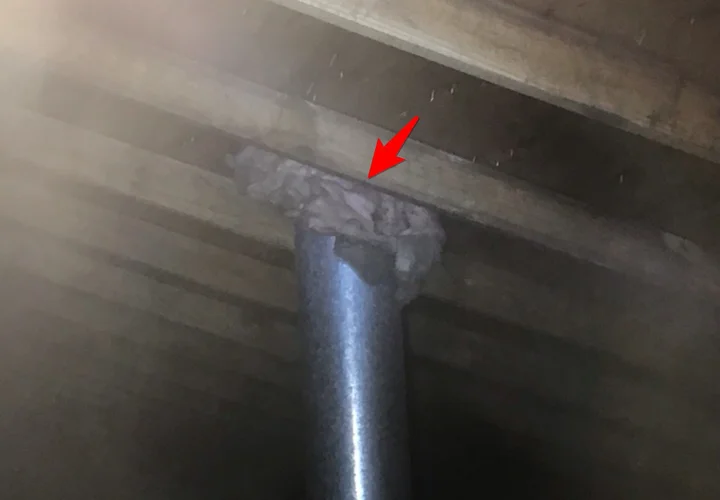 Attic insulation packed against a gas water heater flue