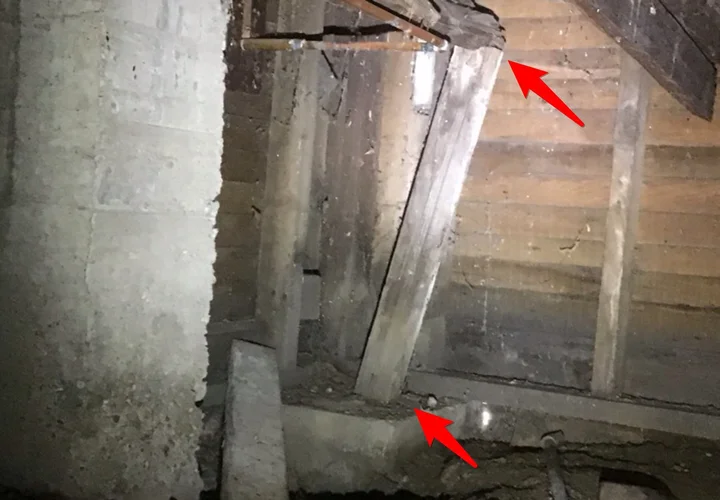 Rotted joists and a damaged support post in a crawlspace