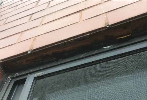Rusting steel lintel above a window in brick masonry