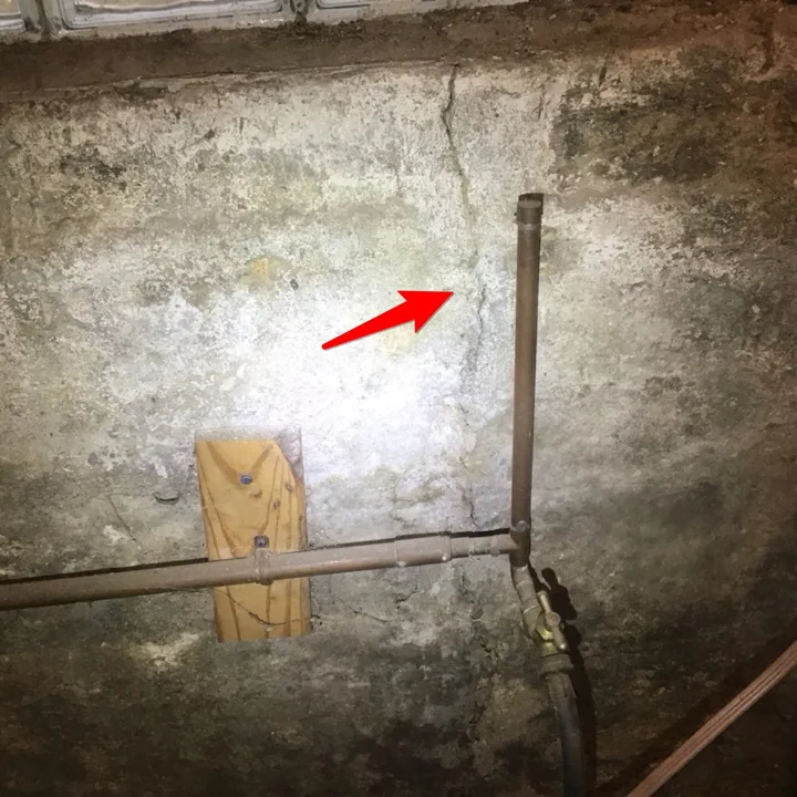 Crack in a poured concrete foundation wall with signs of past moisture intrusion
