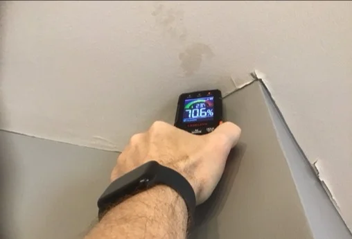 Moisture meter reading elevated at a stained bathroom ceiling