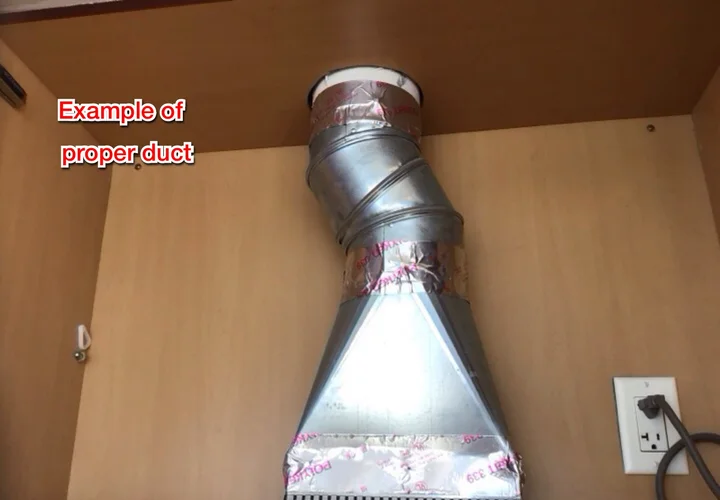 Flexible foil range hood duct in a kitchen cabinet, next to an example of proper smooth metal ducting (photo 2)